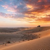 Dubai desert dunes in sunrise and sunset light with a safari vehicle
