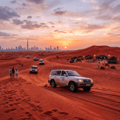 SUVs driving on red sand dunes at sunset with Dubai skyline and desert camp nearby