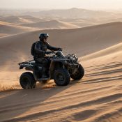 Quad bike rider crossing Dubai desert dunes in early morning light