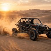 Dune buggy driving across Dubai desert dunes at sunset